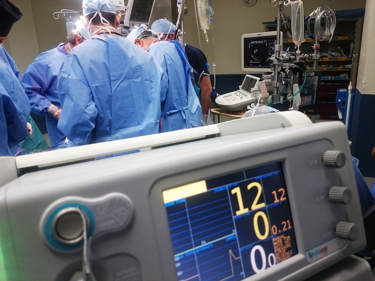 Surgeons operating in the background as a heart rate monitor functions in the foreground